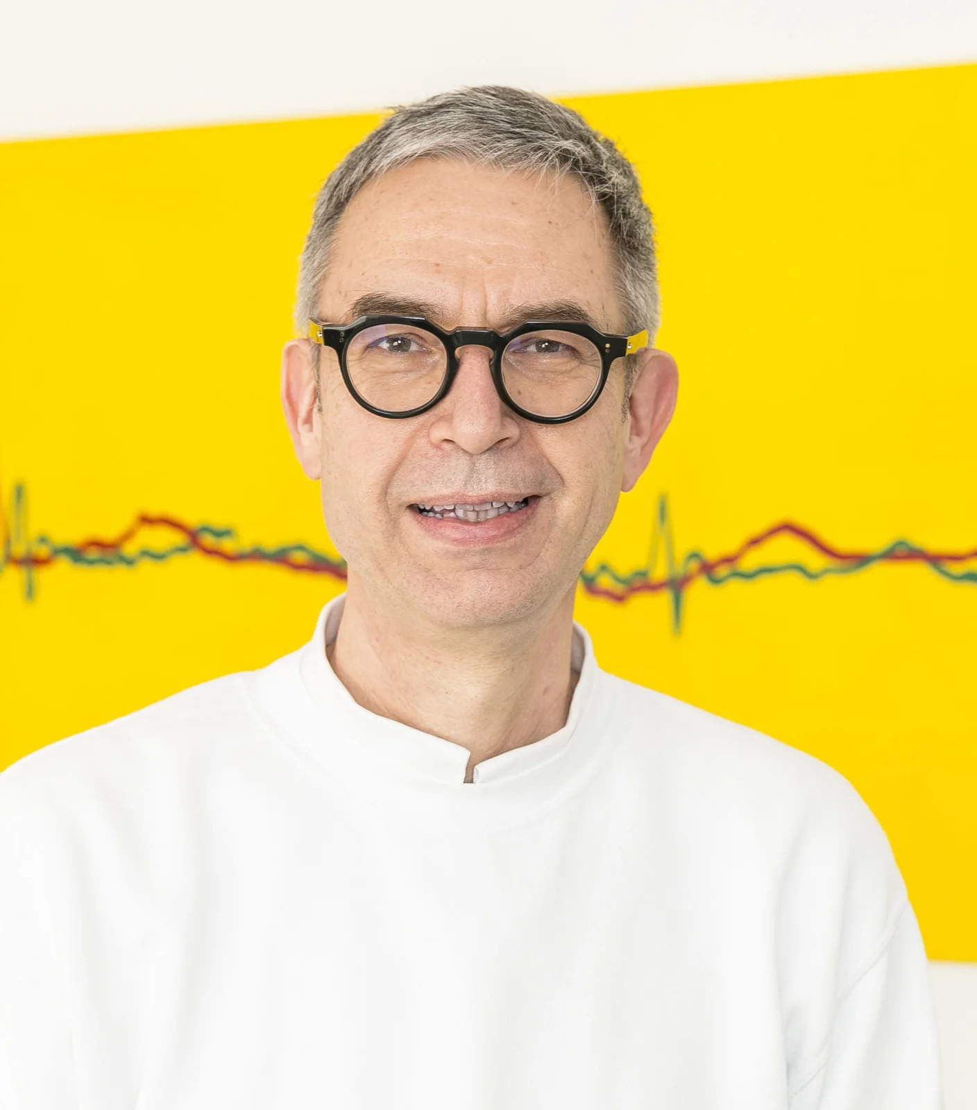 Dr. Robert Denz vor einem gelben EKG-Bild