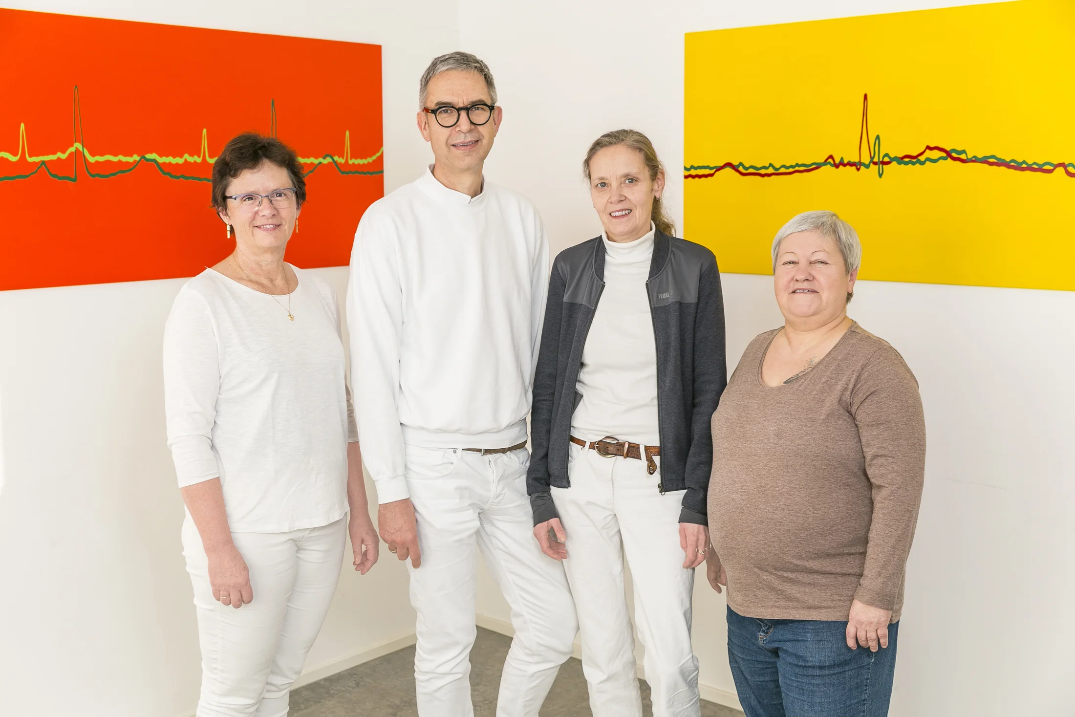 Das Praxisteam von Dr. Denz vor den EKG-Bildern im Wartebereich